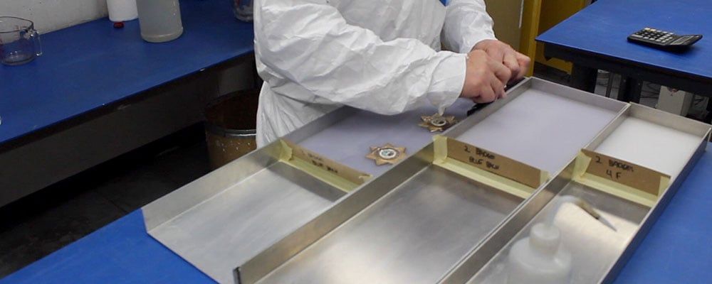 Lucite® police badges on the workbench being cast into molds by an acrylic embedment employee of US Acrylic Awards.